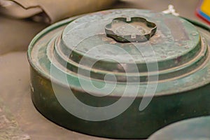 Rusty old anti-tank mine or AT mine, a type of land mine designed to damage or destroy vehicles including tanks and armored fight