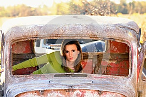 Rusty old auto with young woman inside