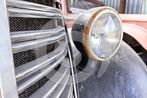 A rusty old car front headlight close up