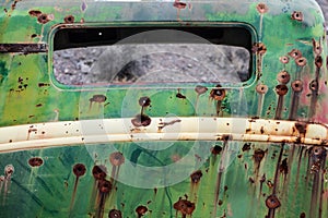 Rusty old car metal with bullet holes.