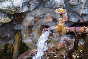 Rusty old faucet on a spring in the village