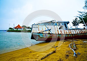 Rusty old fishing boat ship on the quiet yellow sandy beach in the fresh morning sunrise air