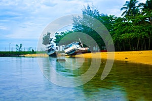 Rusty old fishing boat ship on the quiet yellow sandy beach in the fresh morning sunrise air