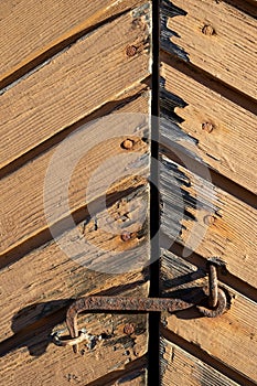 Rusty old hook latch on wooden door exterior