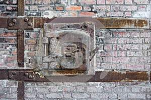 Rusty old metal hatch door of a red brick kiln.