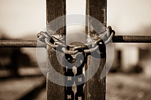 Rusty old padlock with an iron chain at a fence