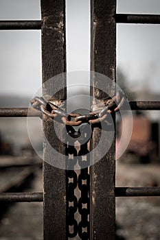 Rusty old padlock with an iron chain at a fence