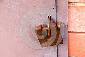 A rusty old padlock is locked on metal doors. No entry, security