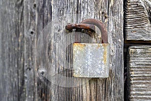 Rusty old padlock on a wooden door of the old house