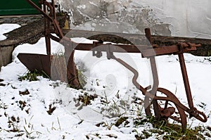 a rusty old plough in a snowy frontyard