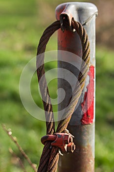 Rusty old steel cable of a former barrier covered with moss