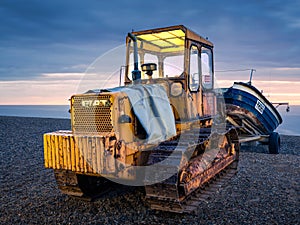 Rusty old tractor towing fishing boat on the beach