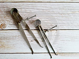 Rusty old tweezers or compasses, on an old wooden table,