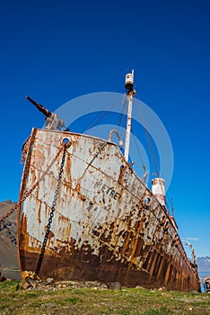 Rusty old whaler beached on grassy shore photo
