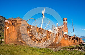 Rusty old whaler beached beside wooden dock