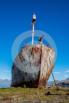 Rusty old whaler beached beside wooden jetty photo