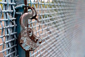 A rusty open lock without a key hangs on a metal fence. Security concept. Selective focus. Copy space