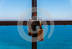 Rusty padlock attached to a balustrade by the sea, a traditional