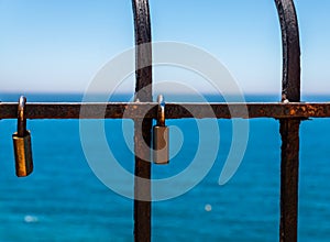 Rusty padlock attached to a balustrade by the sea, a traditional