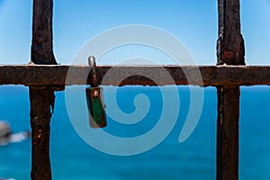 Rusty padlock attached to a balustrade by the sea, a traditional