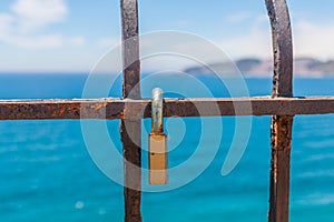 Rusty padlock attached to a balustrade by the sea, a traditional