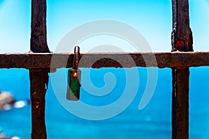 Rusty padlock attached to a balustrade by the sea, a traditional