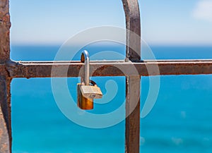 Rusty padlock attached to a balustrade by the sea, a traditional