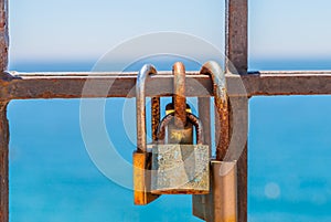 Rusty padlock attached to a balustrade by the sea, a traditional