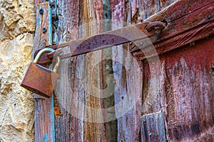 Rusty padlock and hinge on an old door