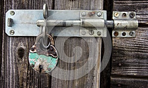 Rusty padlock and latch on old wooden door