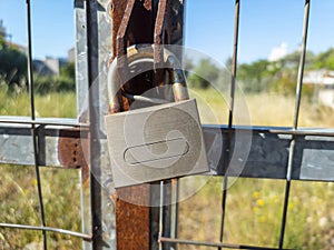 Rusty padlock locked on metal grid fence background