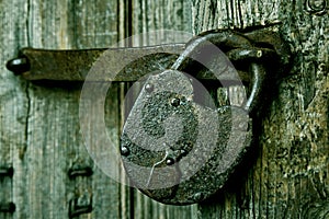 A rusty padlock on an old wooden door.