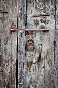 Rusty padlock on an old wooden door of the house