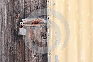Rusty padlocked bolt on old wooden door and painted corrugated iron shed