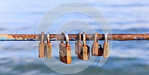 Rusty padlocks closed on peeled railing signaling love. Close up view, blurred background.