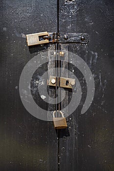 Rusty padlocks and locking bar on an old metal door