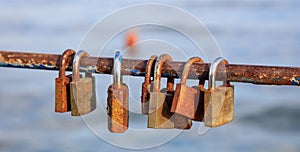 Rusty padlocks has been locked on a peeled railing. Blurred background, close up view with details.