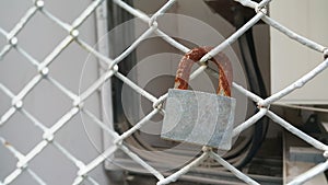 A rusty pedlock hanging on a steel mesh