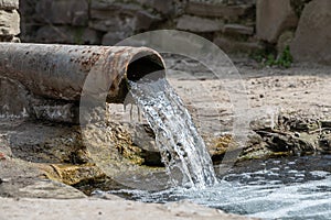 rusty pipe with flowing water into the river.