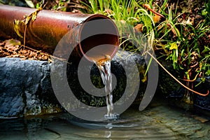 Rusty pipe oozes water, a relic of yesteryears, flows gracefully