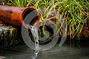 Rusty pipe oozes water, a relic of yesteryears, flows gracefully photo