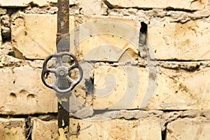 Rusty pipeline valve on brick wall background