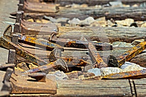 Rusty railroad spikes laying on ground in a pile