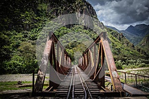 Rusty railway bridge over the river with mountains Surrounding