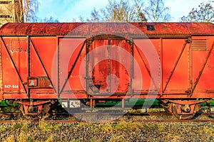 Rusty red metal freight car on disused train tracks at old station