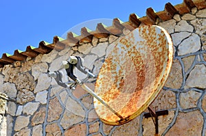 Rusty satellite TV radio internet wifi antenna on the wall of ancient house