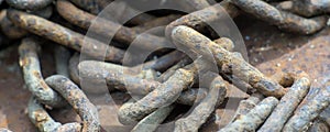 Rusty ship chain on the stone coast. Close up.