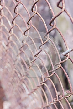 Rusty steel chain link or wire mesh as boundary wall. There is still concrete block wall behind the mesh.