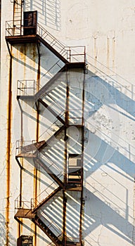 Rusty steel staircase is built on the outer wall of an abandoned factory