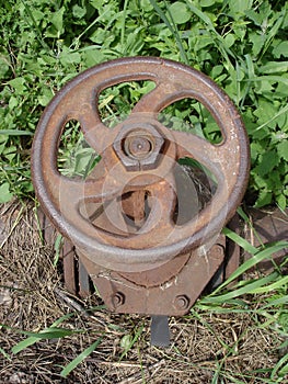 Rusty steel water tap in the green and dry grass